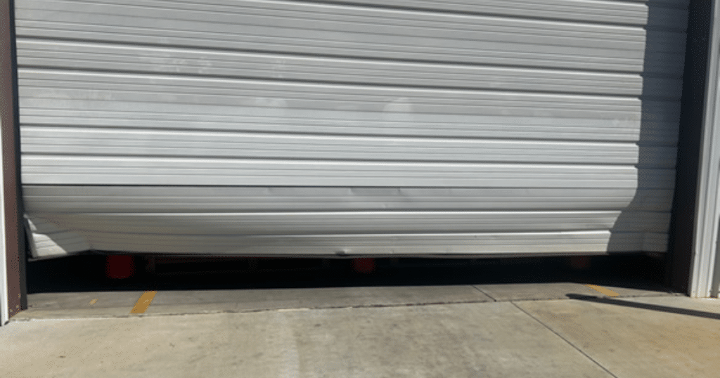 Damaged metal garage door bent inward.