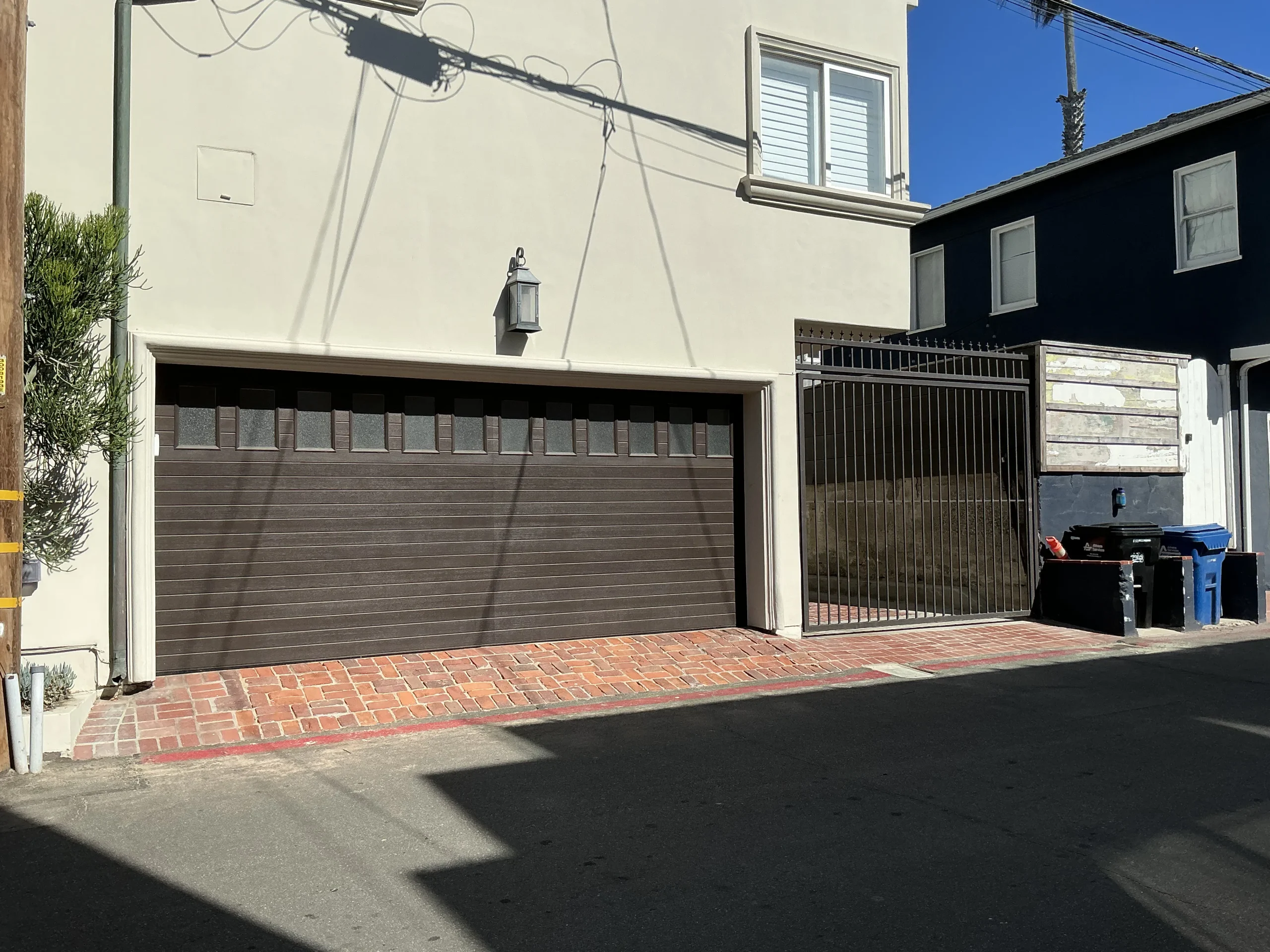 A closed dark brown panel garage door on a stucco home, demonstrating when you might need to open your garage door manually.