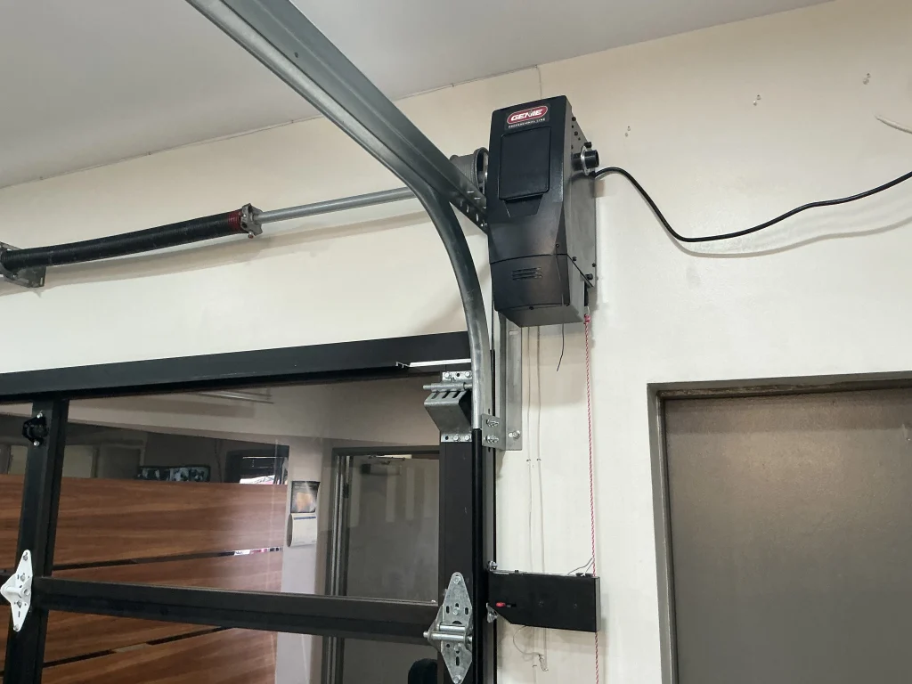 An interior view of a modern glass garage door with a wall-mounted Genie opener and torsion spring system, useful for troubleshooting garage door won't close causes