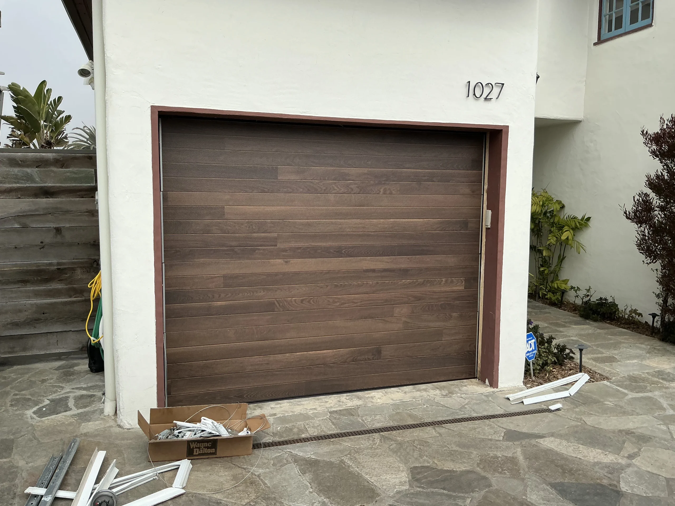 A modern faux-wood finish door installed on a stucco home, demonstrating the stylish durability of vinyl garage doors.
