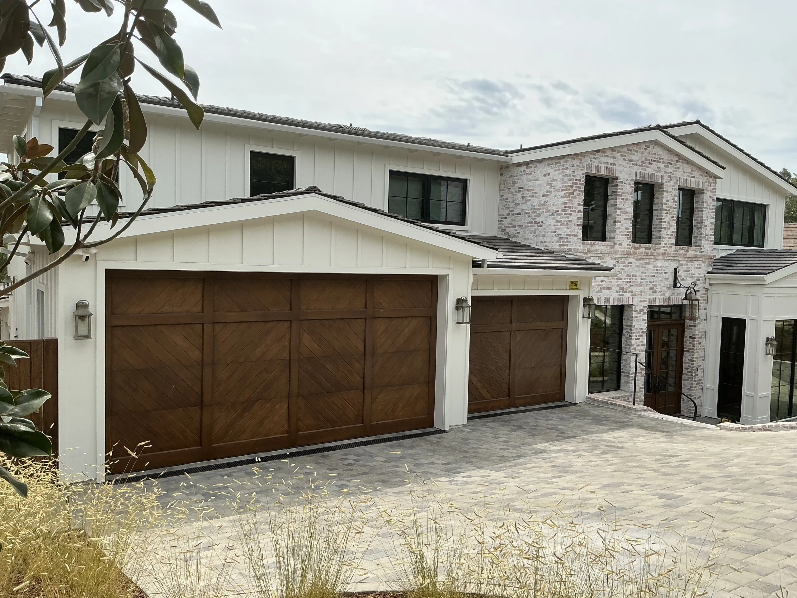 A luxury home featuring beautifully finished dual wooden garage doors with chevron patterned panels, highlighting essential maintenance tips for wooden garage doors in Torrance, CA.