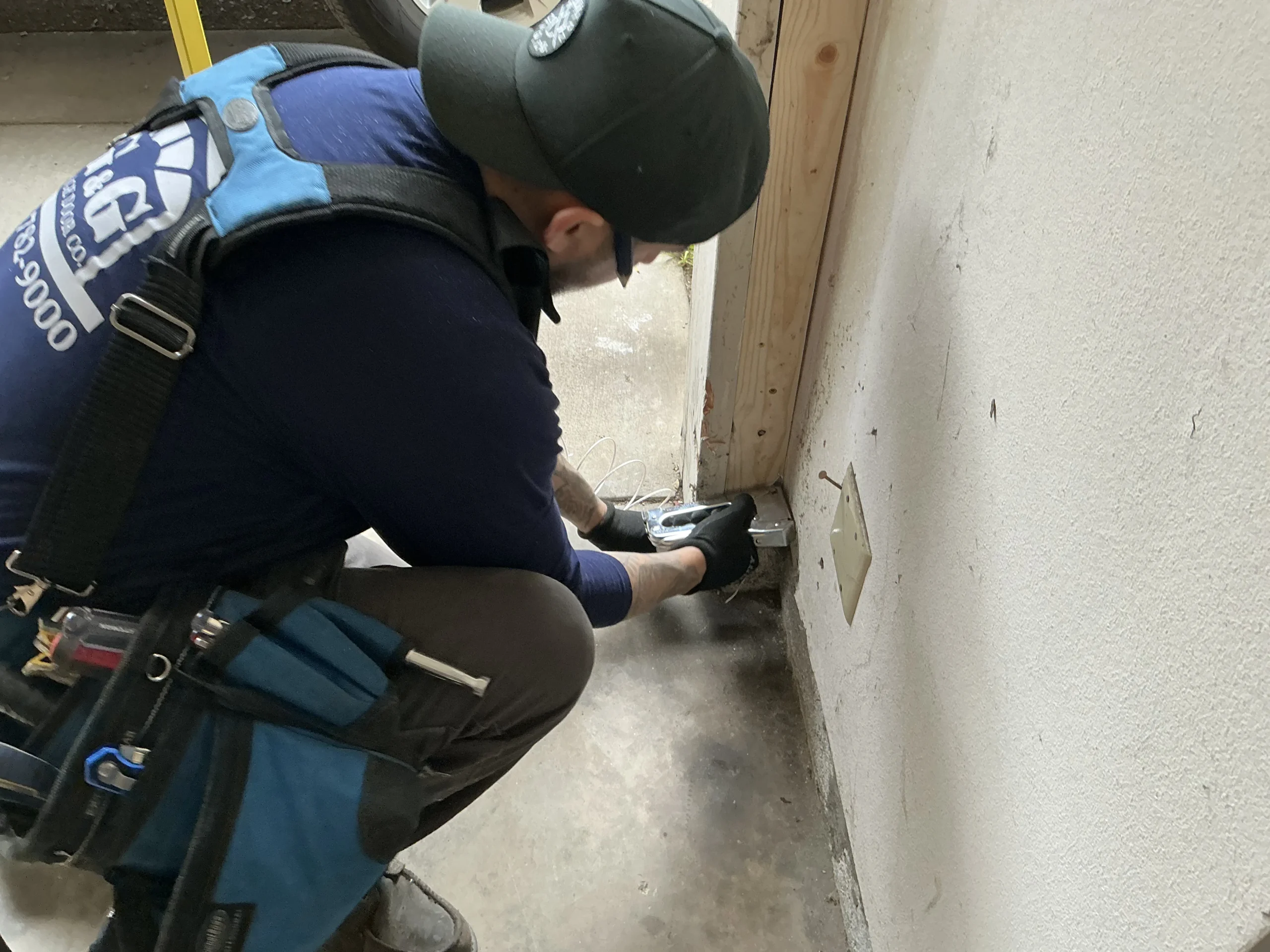 A technician kneeling to service a safety sensor, representing essential 9x8 garage door maintenance.