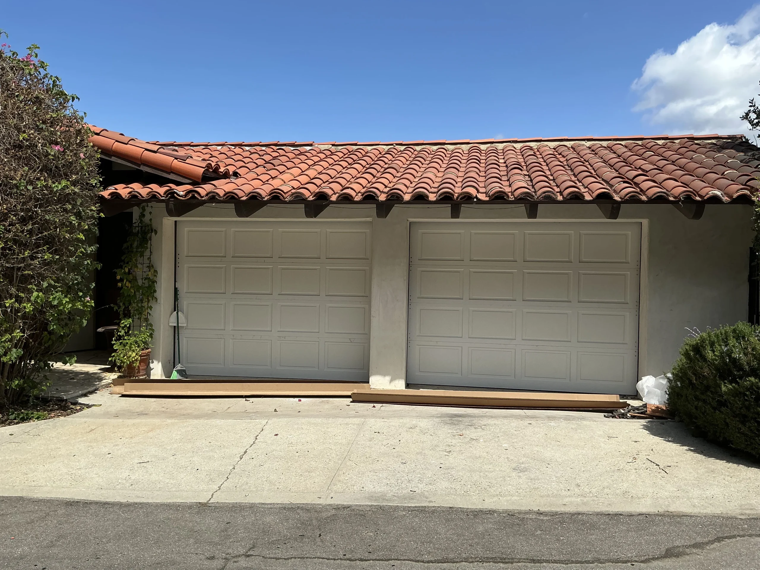 Two newly installed white raised-panel sectional doors on a Spanish-style home, showcasing durable 9x8 garage door material options.