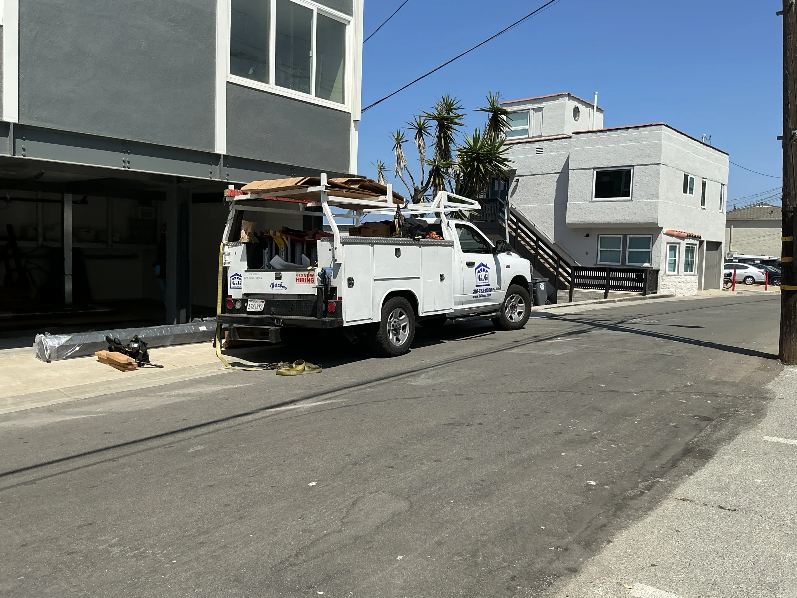A professional service truck parked on a street outside a residential building during a newly scheduled overhead garage door installation.