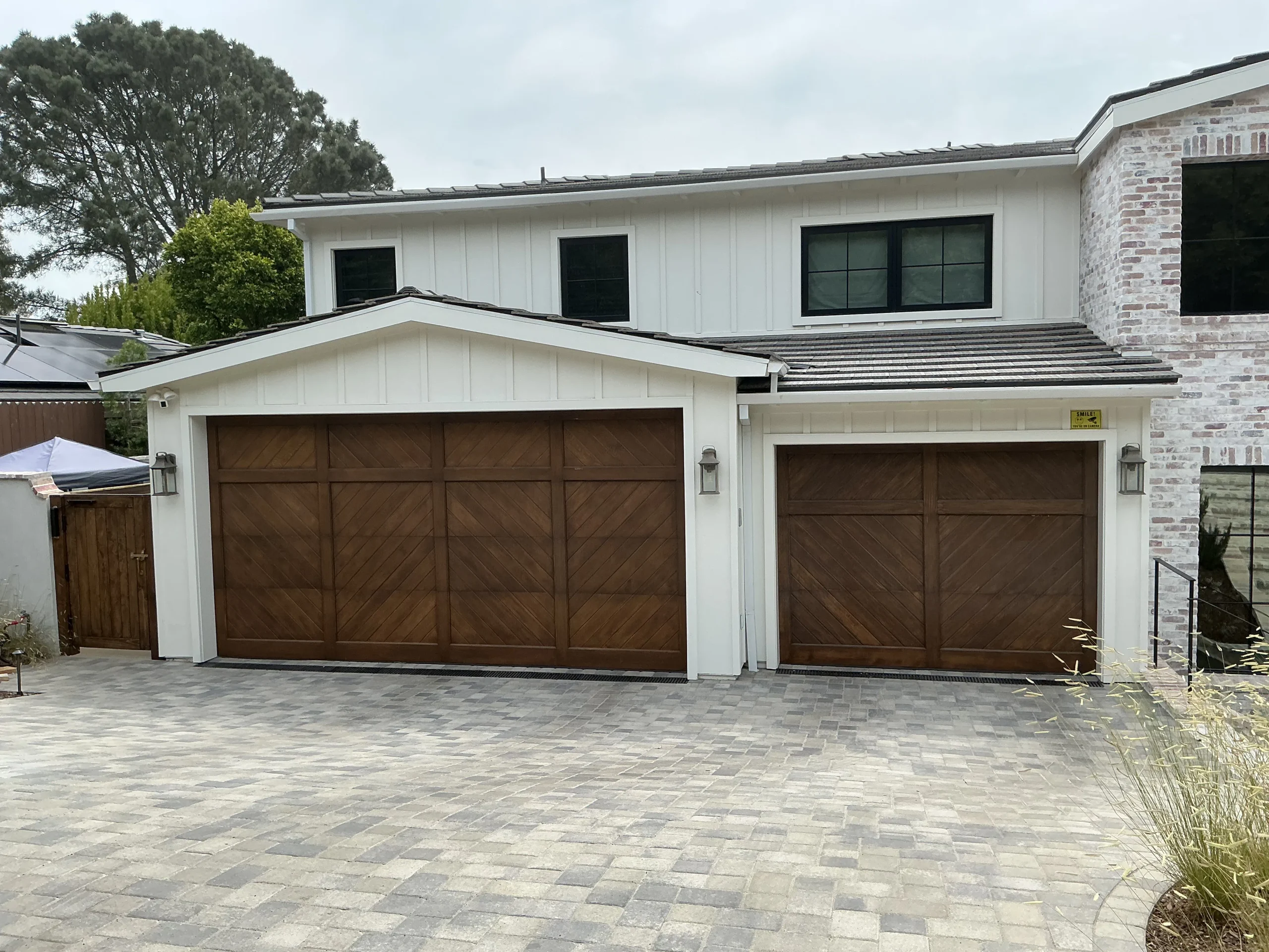 A side-by-side view of dual carriage-style sectional wooden doors featuring a chevron design paneling, showcasing custom overhead garage door types.
