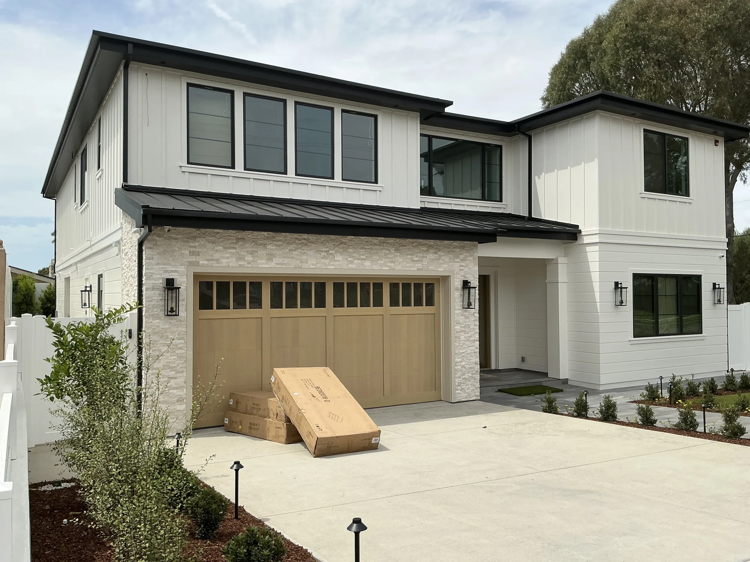 A stylish light-brown carriage-style door installed on a modern white home, showcasing a newly completed residential garage door in Torrance, CA.