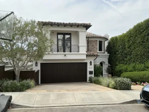 A wide, dark brown double garage door installed on a luxury Spanish-style white stucco house, demonstrating how to choose the right garage door width.