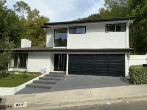 A modern two-story white home featuring a newly installed black vinyl garage door, showcasing a completed vinyl garage door installation.