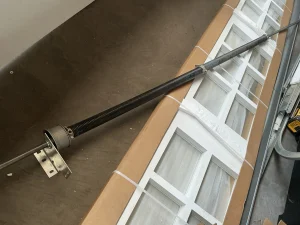 A new garage door torsion spring assembly laying on top of a packaged white panel door, ready for a garage door spring replacement.